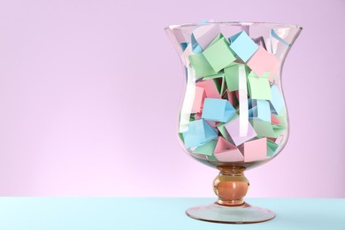 Photo of Bright paper pieces in glass jar on color background. Space for text