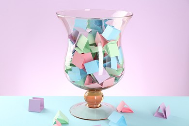 Photo of Bright paper pieces in glass jar on color background, closeup