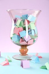 Photo of Bright paper pieces in glass jar on color background, closeup