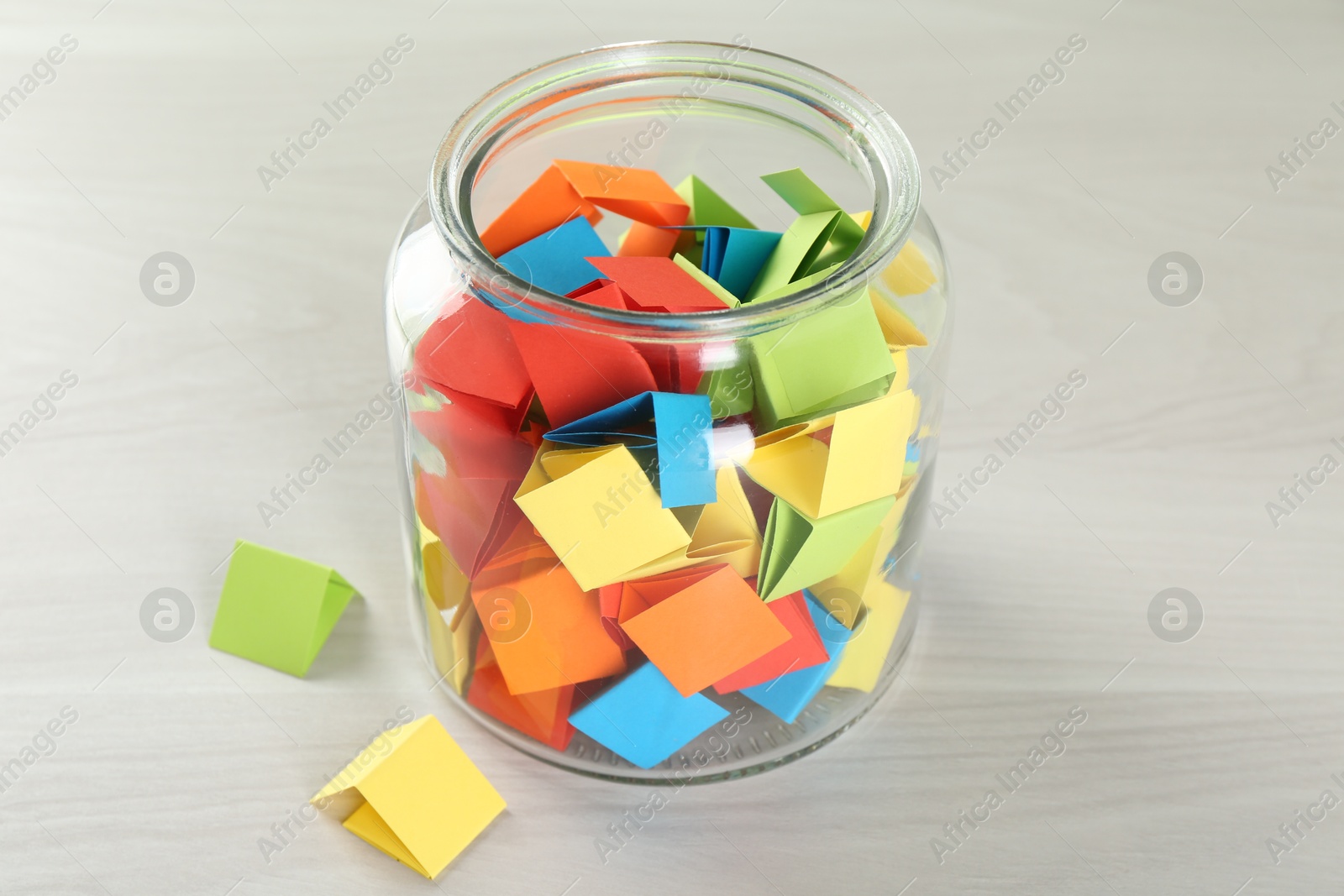 Colorful paper pieces in glass jar on wooden table, closeup Photo of Colorful paper pieces in glass jar on wooden table, closeup