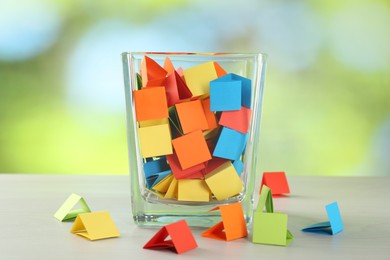 Photo of Colorful paper pieces in glass jar on wooden table against blurred background