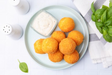 Photo of Delicious fried croquette balls, sauce and basil on light table, flat lay