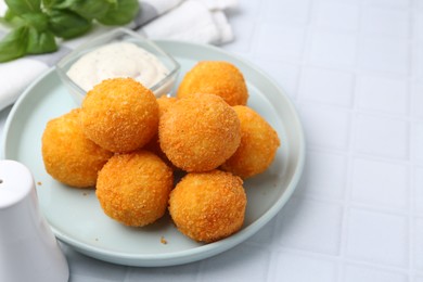 Photo of Delicious fried croquette balls and sauce on light tiled table, closeup