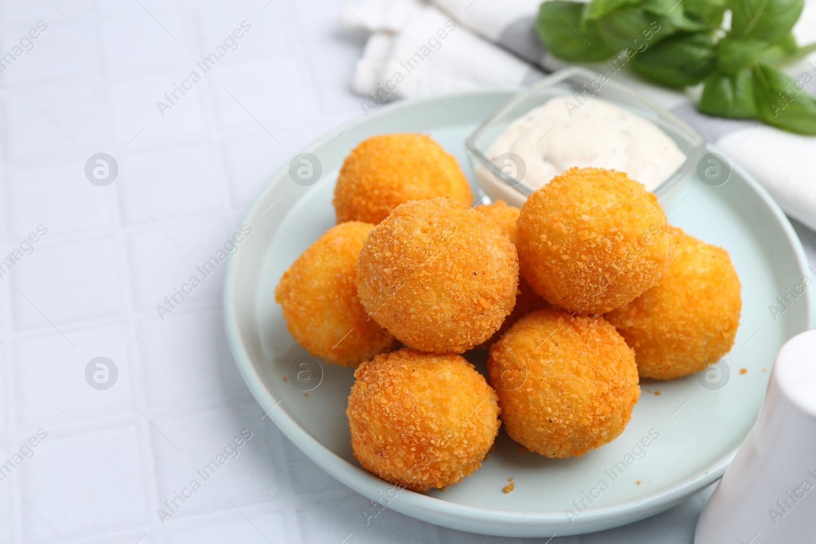 Delicious fried croquette balls and sauce on light tiled table, closeup Photo of Delicious fried croquette balls and sauce on light tiled table, closeup