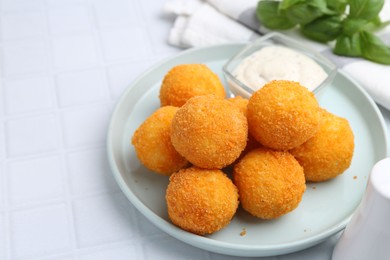 Photo of Delicious fried croquette balls and sauce on light tiled table, closeup