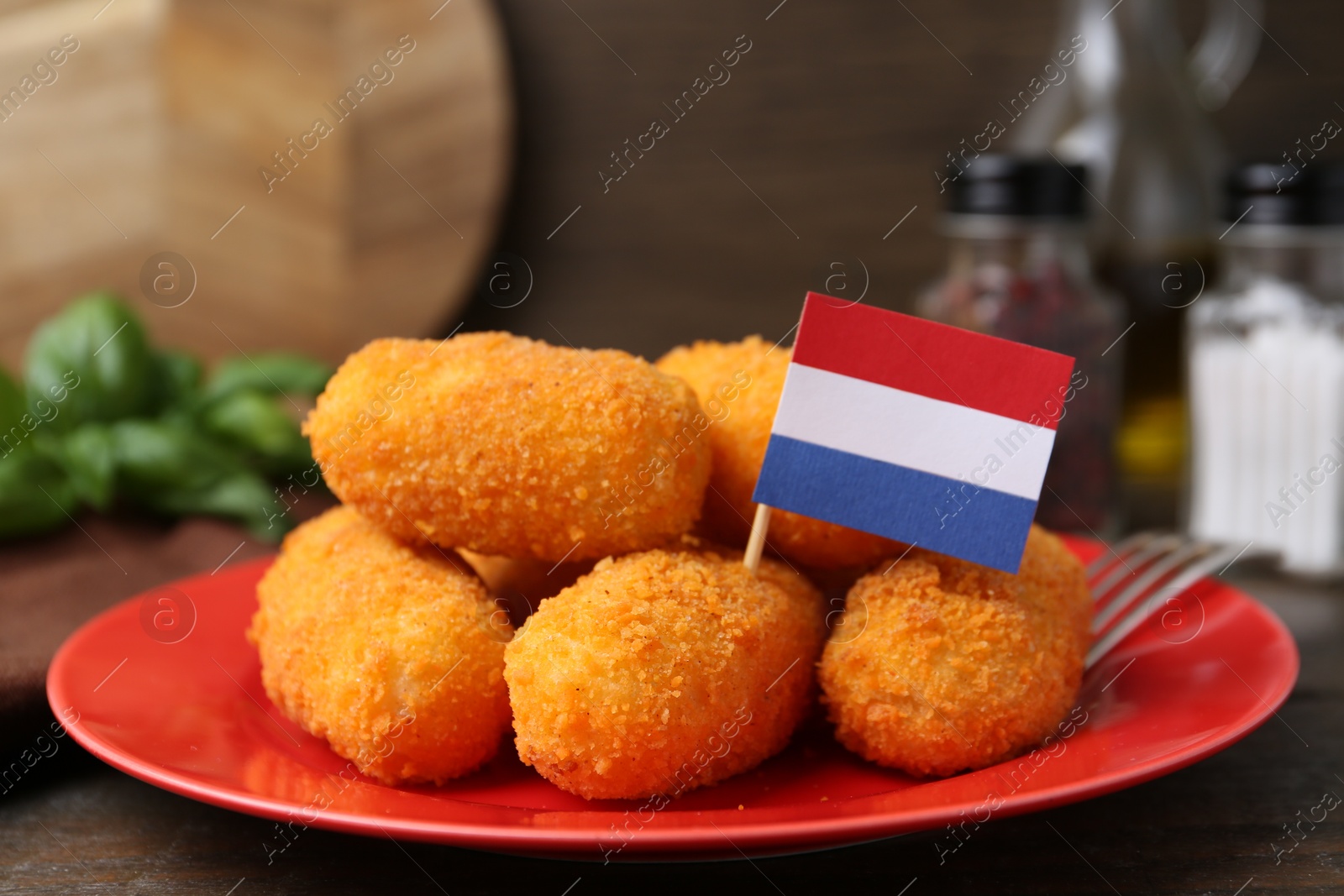 Photo of Delicious fried croquettes and flag of Netherlands on table, closeup