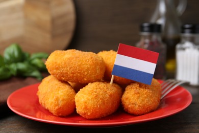 Photo of Delicious fried croquettes and flag of Netherlands on table, closeup