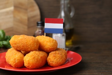 Photo of Delicious fried croquettes and flag of Netherlands on table, closeup
