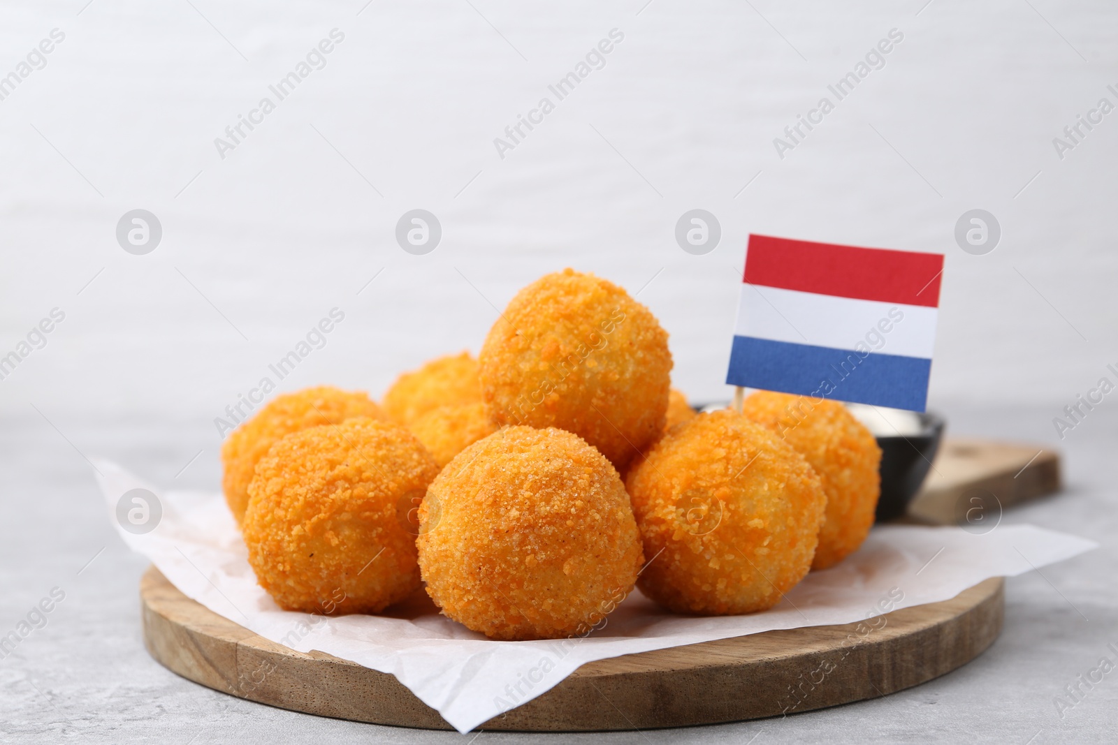 Photo of Delicious fried croquette balls and flag of Netherlands on gray table, closeup
