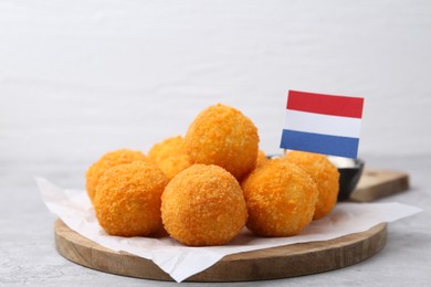 Photo of Delicious fried croquette balls and flag of Netherlands on gray table, closeup