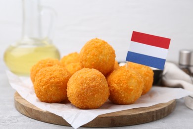 Photo of Delicious fried croquette balls and flag of Netherlands on gray table, closeup