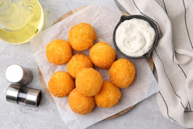 Photo of Delicious fried croquette balls, sauce, oil and spices on gray textured table, flat lay