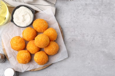 Photo of Delicious fried croquette balls, sauce, oil and spices on gray textured table, flat lay. Space for text