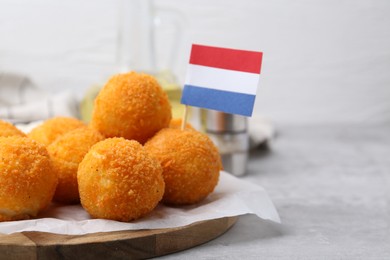 Photo of Delicious fried croquette balls and flag of Netherlands on gray table, closeup
