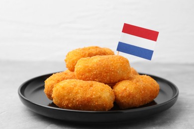 Photo of Delicious fried croquettes and flag of Netherlands on gray table, closeup