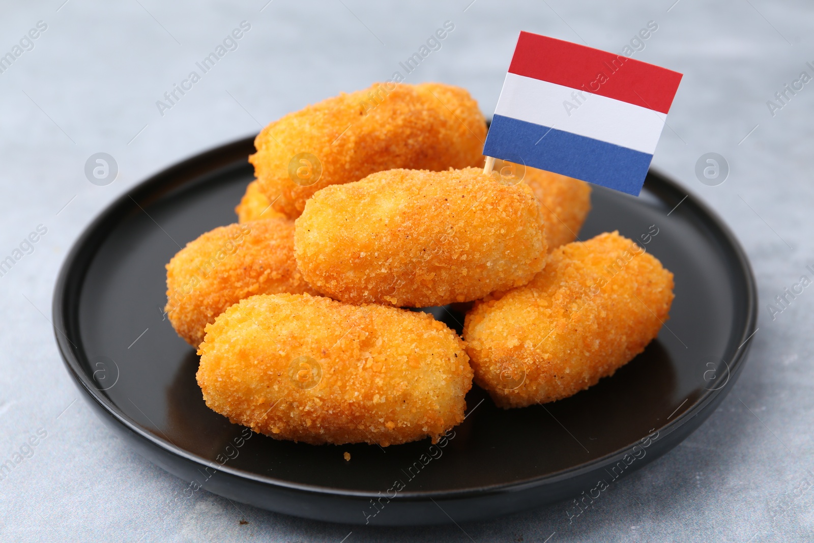 Delicious fried croquettes and flag of Netherlands on gray table, closeup Photo of Delicious fried croquettes and flag of Netherlands on gray table, closeup