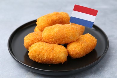 Photo of Delicious fried croquettes and flag of Netherlands on gray table, closeup