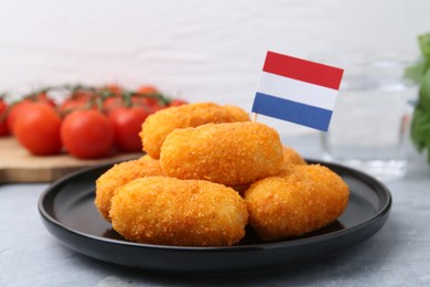 Photo of Delicious fried croquettes and flag of Netherlands on gray table, closeup