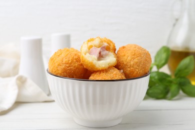 Photo of Delicious fried croquette balls in bowl on white wooden table, closeup