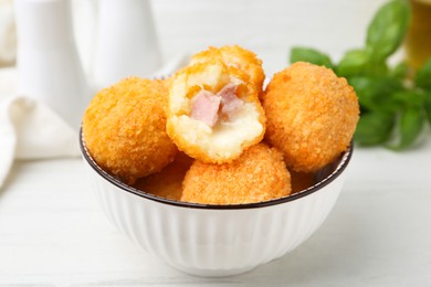 Photo of Delicious fried croquette balls in bowl on white wooden table, closeup