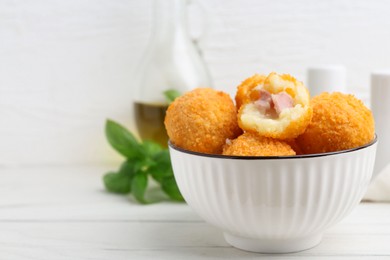 Photo of Delicious fried croquette balls in bowl on white wooden table, closeup. Space for text