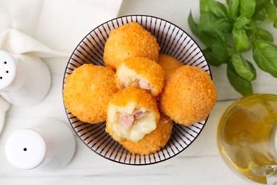 Photo of Delicious fried croquette balls in bowl and spices on white wooden table, flat lay
