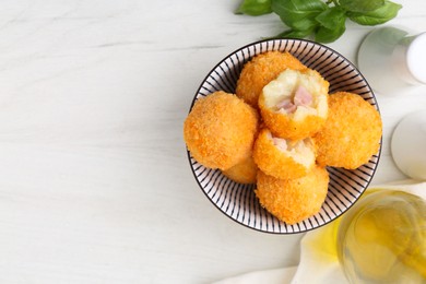 Photo of Delicious fried croquette balls in bowl and spices on white wooden table, flat lay. Space for text