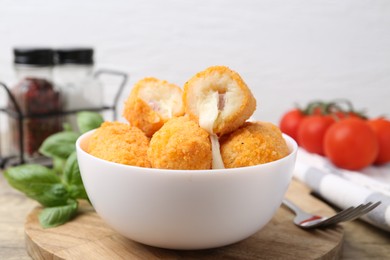 Photo of Delicious fried croquettes in bowl, tomatoes and spices on table, closeup