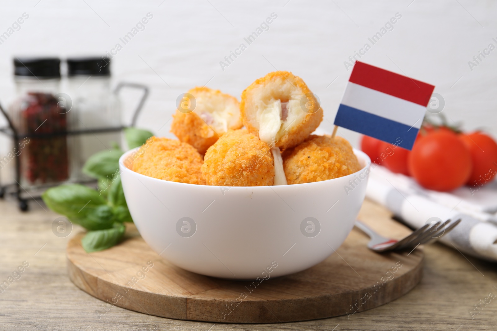 Delicious fried croquettes in bowl and flag of Netherlands on wooden table, closeup Photo of Delicious fried croquettes in bowl and flag of Netherlands on wooden table, closeup