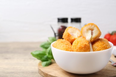 Photo of Delicious fried croquettes in bowl on wooden table, closeup. Space for text