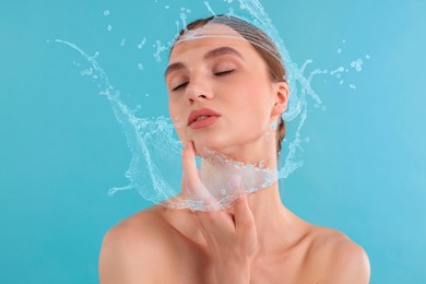 Image of Woman with smooth skin and water splashes against light blue background