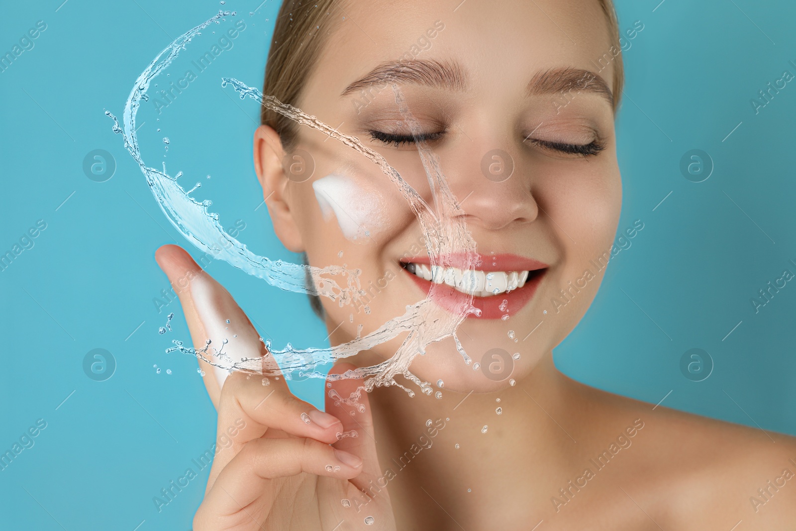 Young woman washing face with cleansing foam and water splashes on light blue background Image of Young woman washing face with cleansing foam and water splashes on light blue background