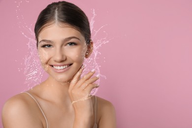 Image of Young woman with smooth skin and water splashes on pink background. Space for text