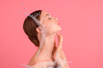 Image of Young woman with smooth skin and water splashes on pink background. Space for text