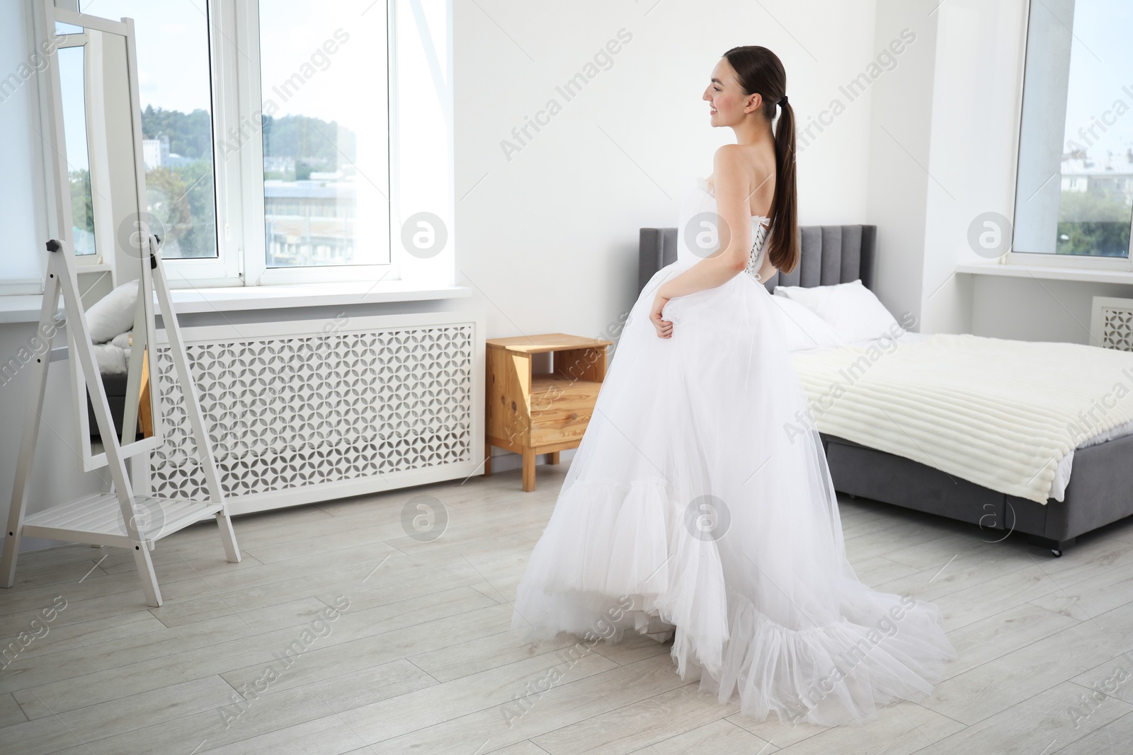 Dreams come true. Woman wearing beautiful wedding dress looking at herself in mirror indoors Photo of Dreams come true. Woman wearing beautiful wedding dress looking at herself in mirror indoors