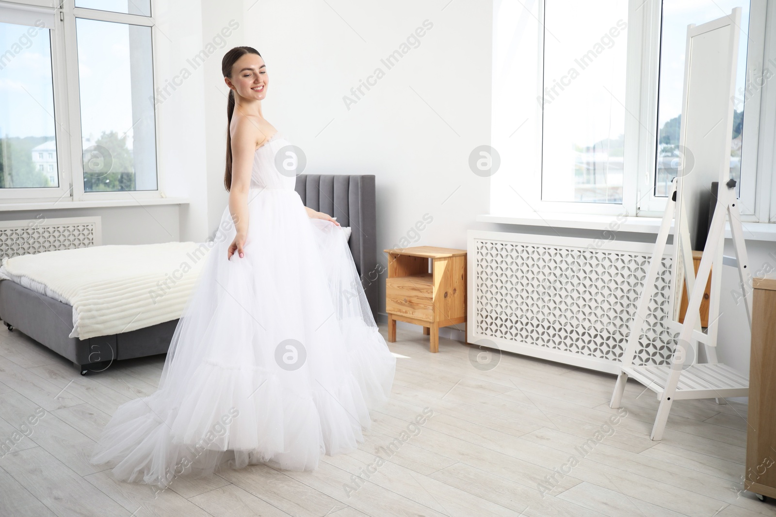 Dreams come true. Woman wearing beautiful wedding dress looking at herself in mirror indoors Photo of Dreams come true. Woman wearing beautiful wedding dress looking at herself in mirror indoors