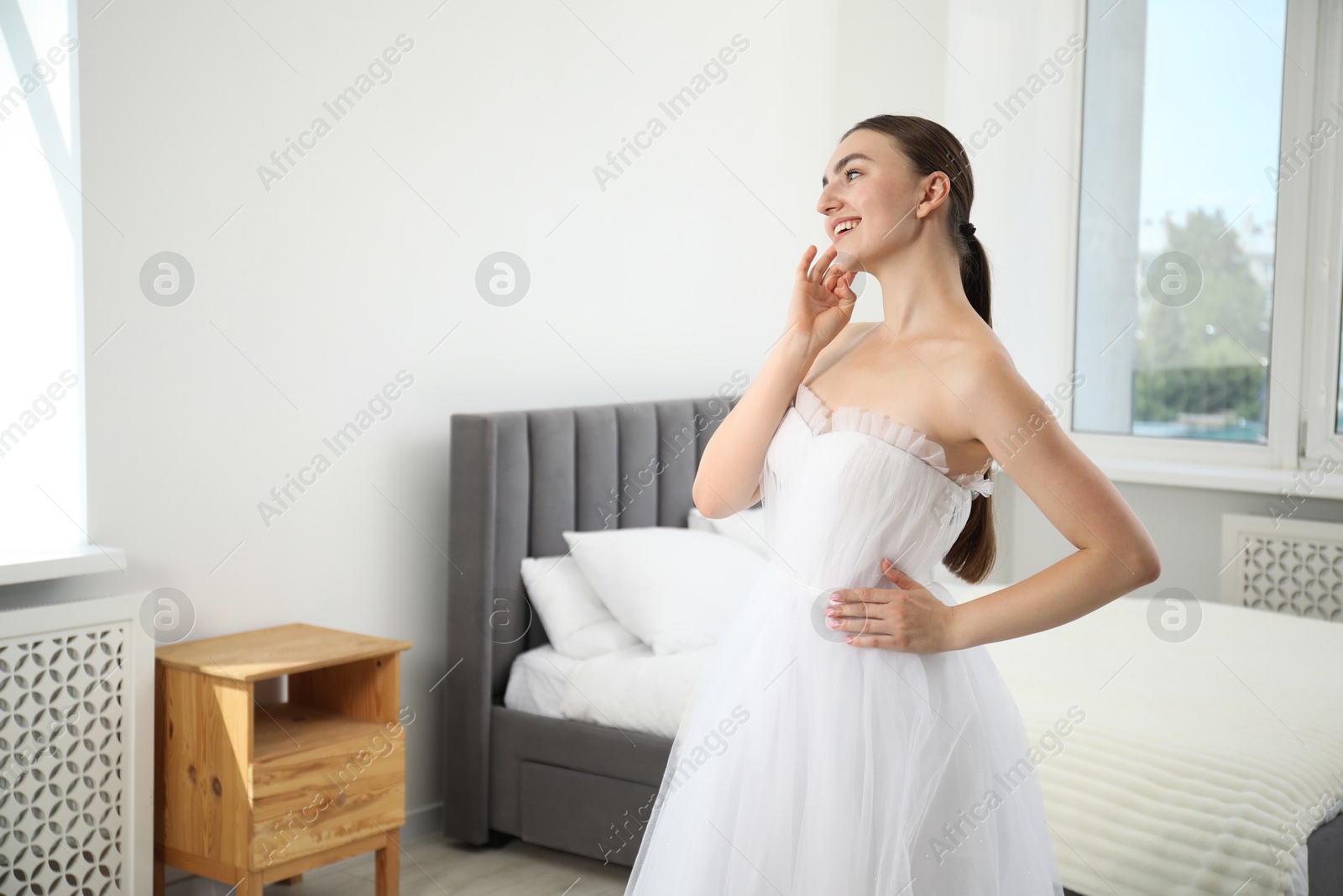 Dreams come true. Woman in beautiful wedding dress at home, space for text Photo of Dreams come true. Woman in beautiful wedding dress at home, space for text
