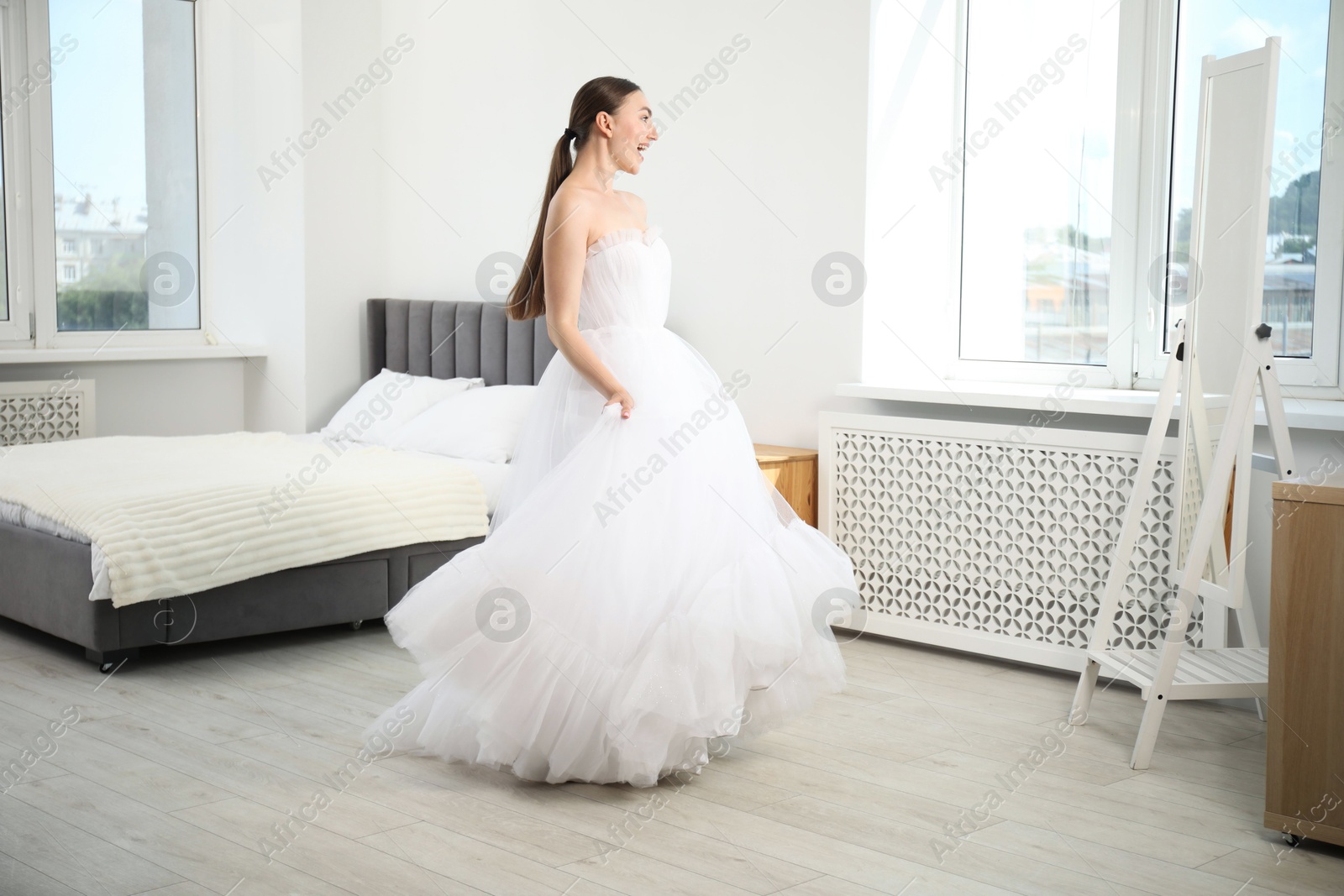 Dreams come true. Woman wearing beautiful wedding dress looking at herself in mirror indoors Photo of Dreams come true. Woman wearing beautiful wedding dress looking at herself in mirror indoors