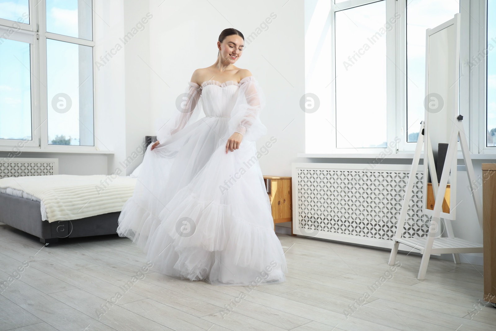Dreams come true. Woman wearing beautiful wedding dress looking at herself in mirror indoors Photo of Dreams come true. Woman wearing beautiful wedding dress looking at herself in mirror indoors