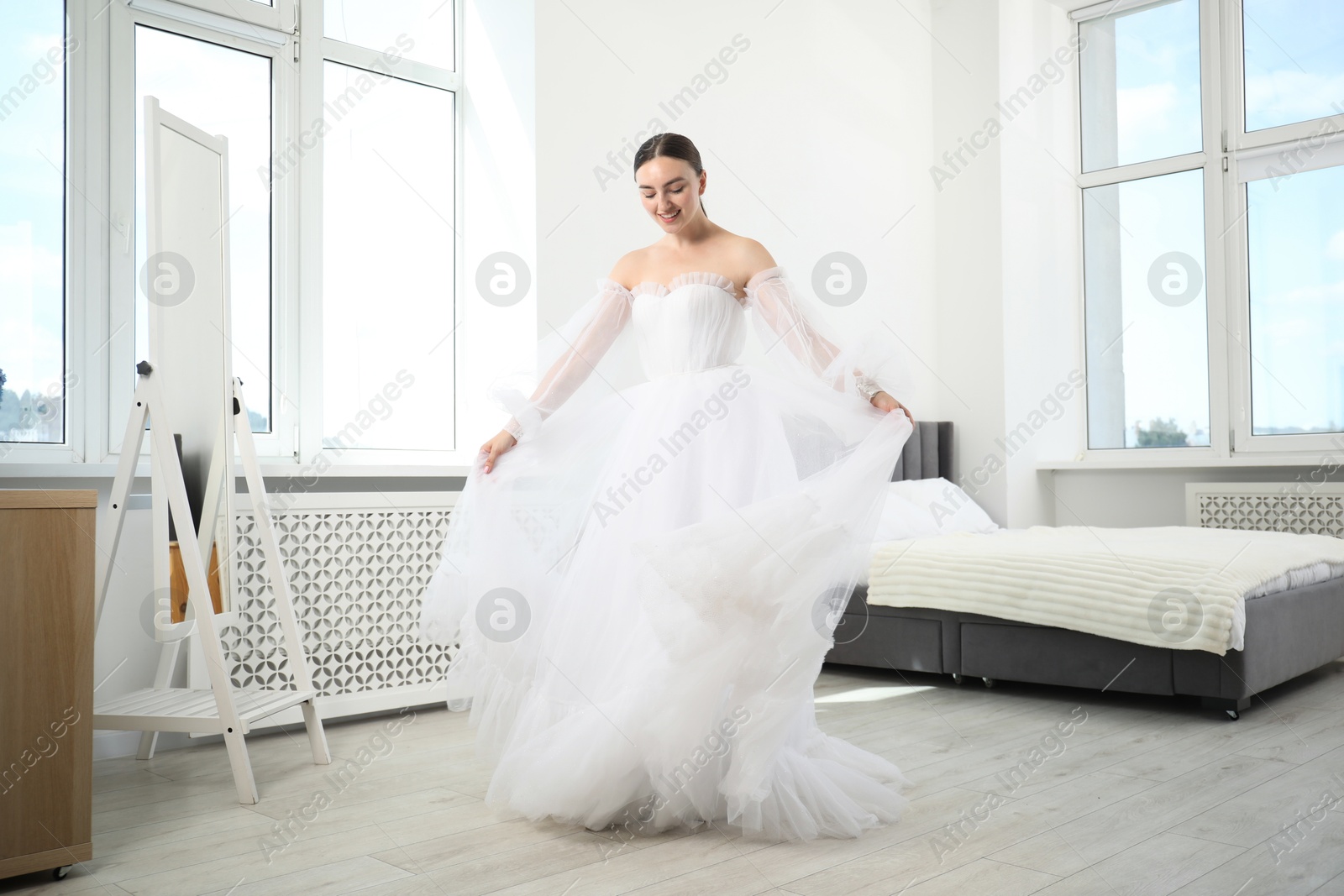 Dreams come true. Woman wearing beautiful wedding dress looking at herself in mirror indoors Photo of Dreams come true. Woman wearing beautiful wedding dress looking at herself in mirror indoors