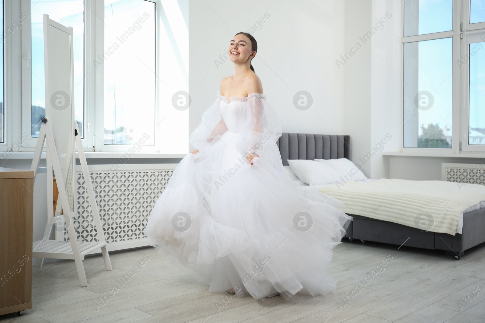 Dreams come true. Woman wearing beautiful wedding dress looking at herself in mirror indoors Photo of Dreams come true. Woman wearing beautiful wedding dress looking at herself in mirror indoors