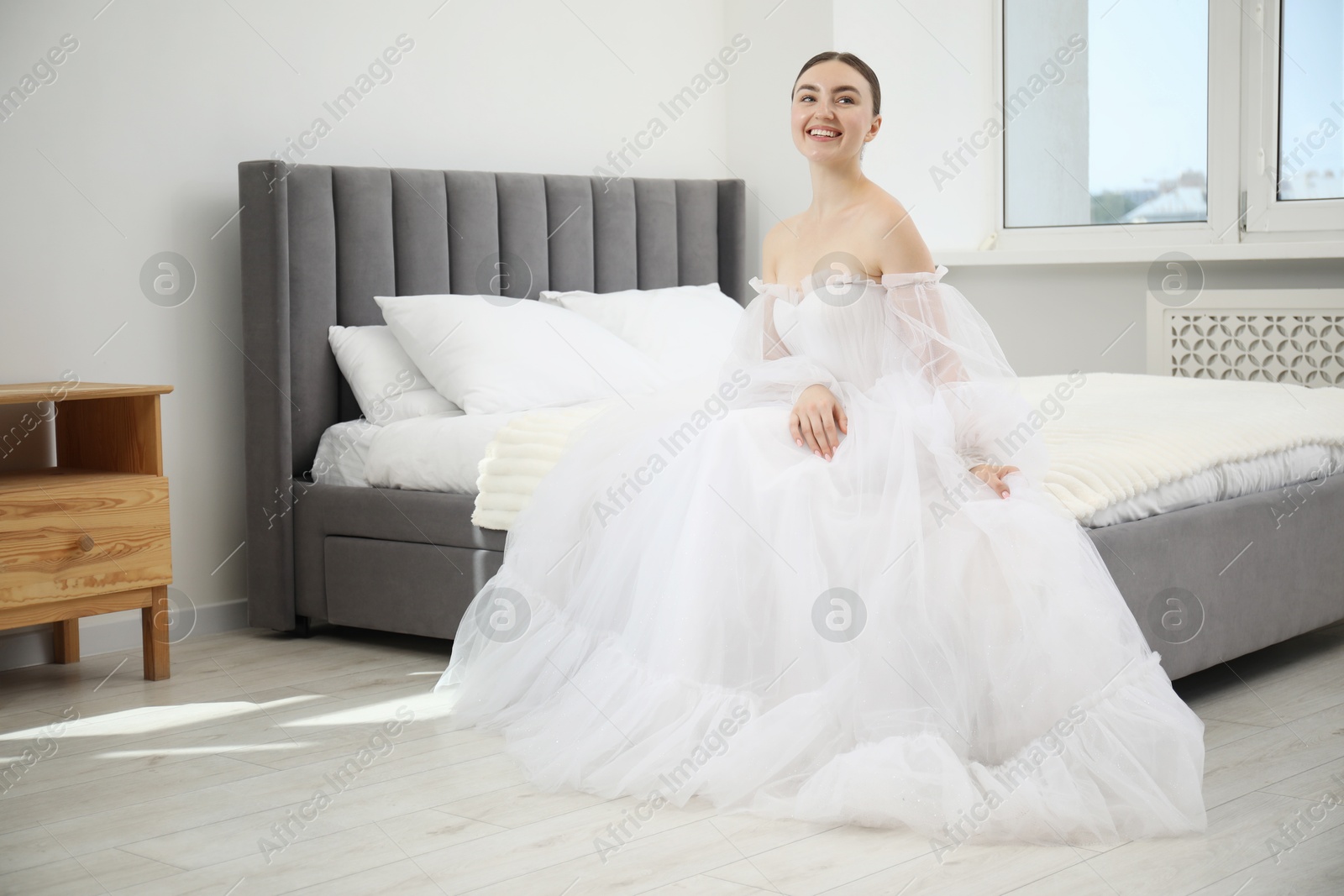 Dreams come true. Woman in beautiful wedding dress on bed at home Photo of Dreams come true. Woman in beautiful wedding dress on bed at home