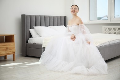 Photo of Dreams come true. Woman in beautiful wedding dress on bed at home