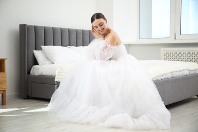 Photo of Dreams come true. Woman in beautiful wedding dress on bed at home