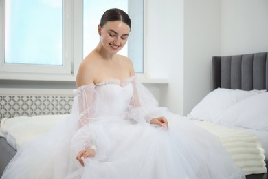 Photo of Dreams come true. Woman in beautiful wedding dress on bed at home