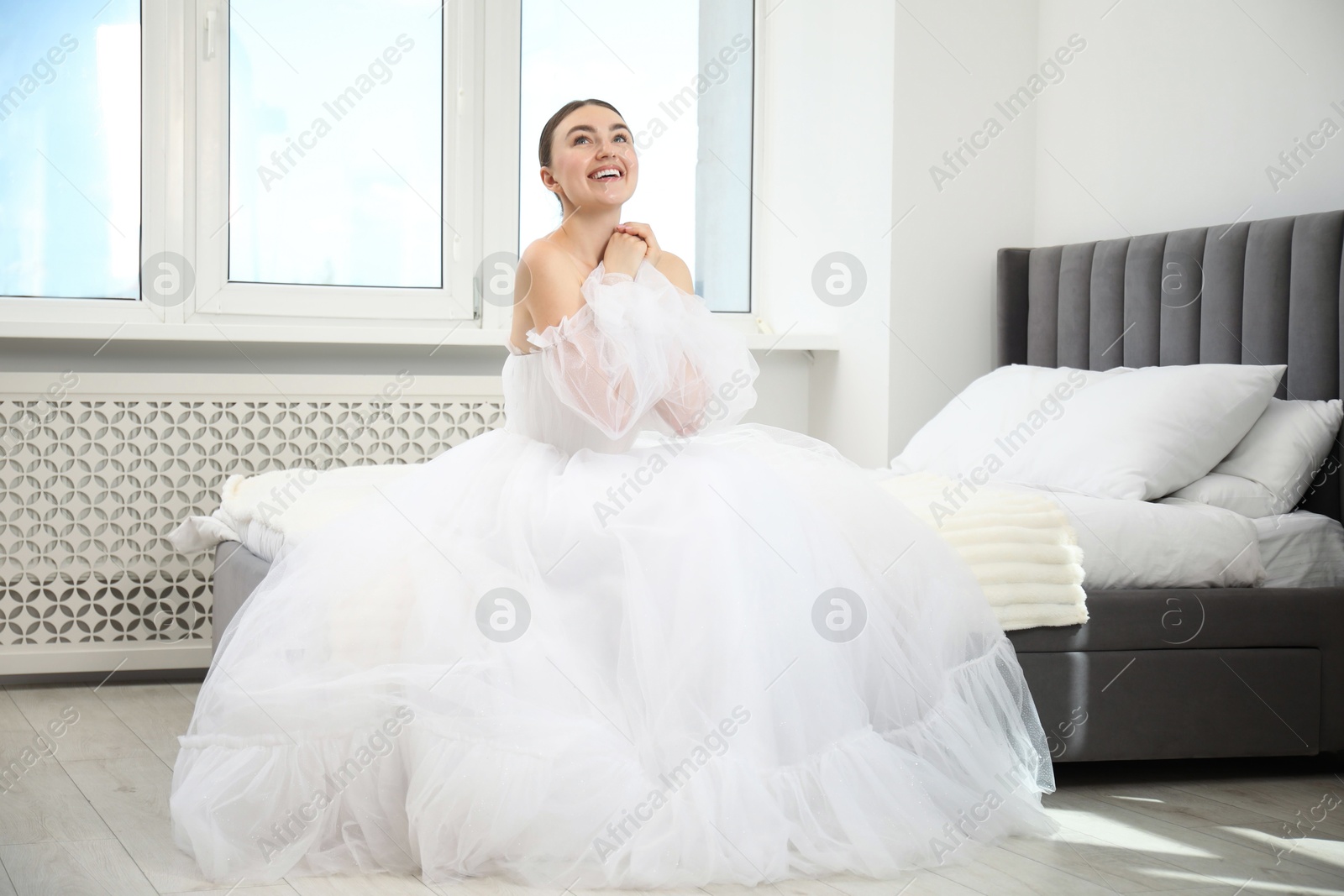 Dreams come true. Woman in beautiful wedding dress on bed at home Photo of Dreams come true. Woman in beautiful wedding dress on bed at home