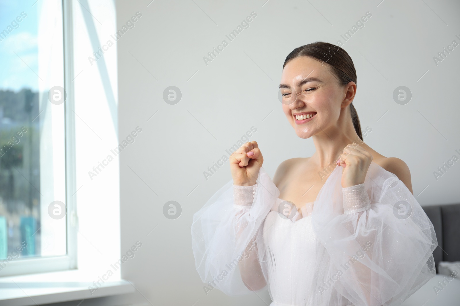 Dreams come true. Woman in beautiful wedding dress at home, space for text Photo of Dreams come true. Woman in beautiful wedding dress at home, space for text