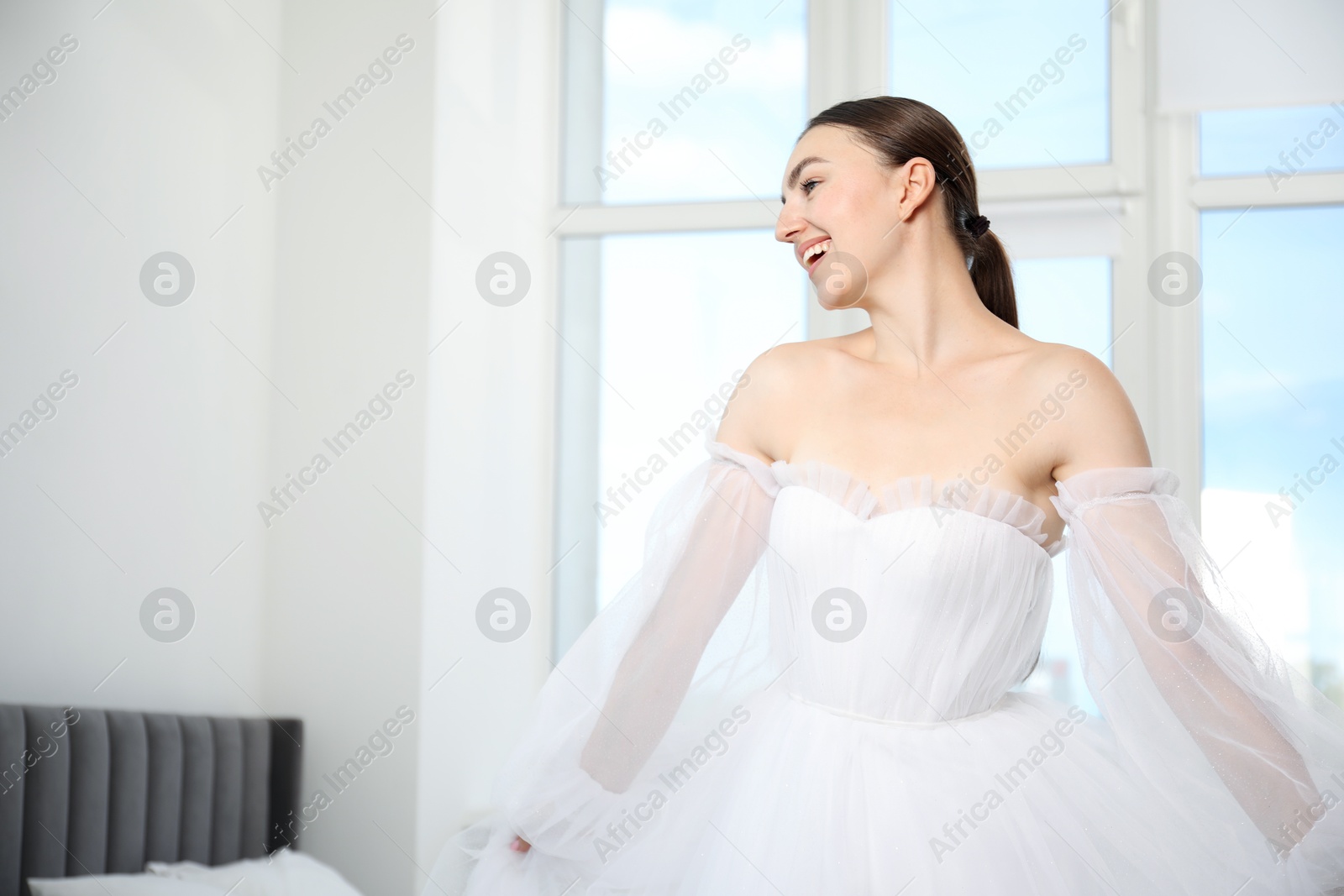 Dreams come true. Woman in beautiful wedding dress at home, space for text Photo of Dreams come true. Woman in beautiful wedding dress at home, space for text
