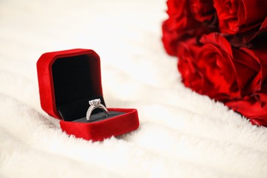 Photo of Dreams come true. Beautiful engagement ring in box and flowers on light plaid, closeup