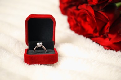 Photo of Dreams come true. Beautiful engagement ring in box and flowers on light plaid, closeup
